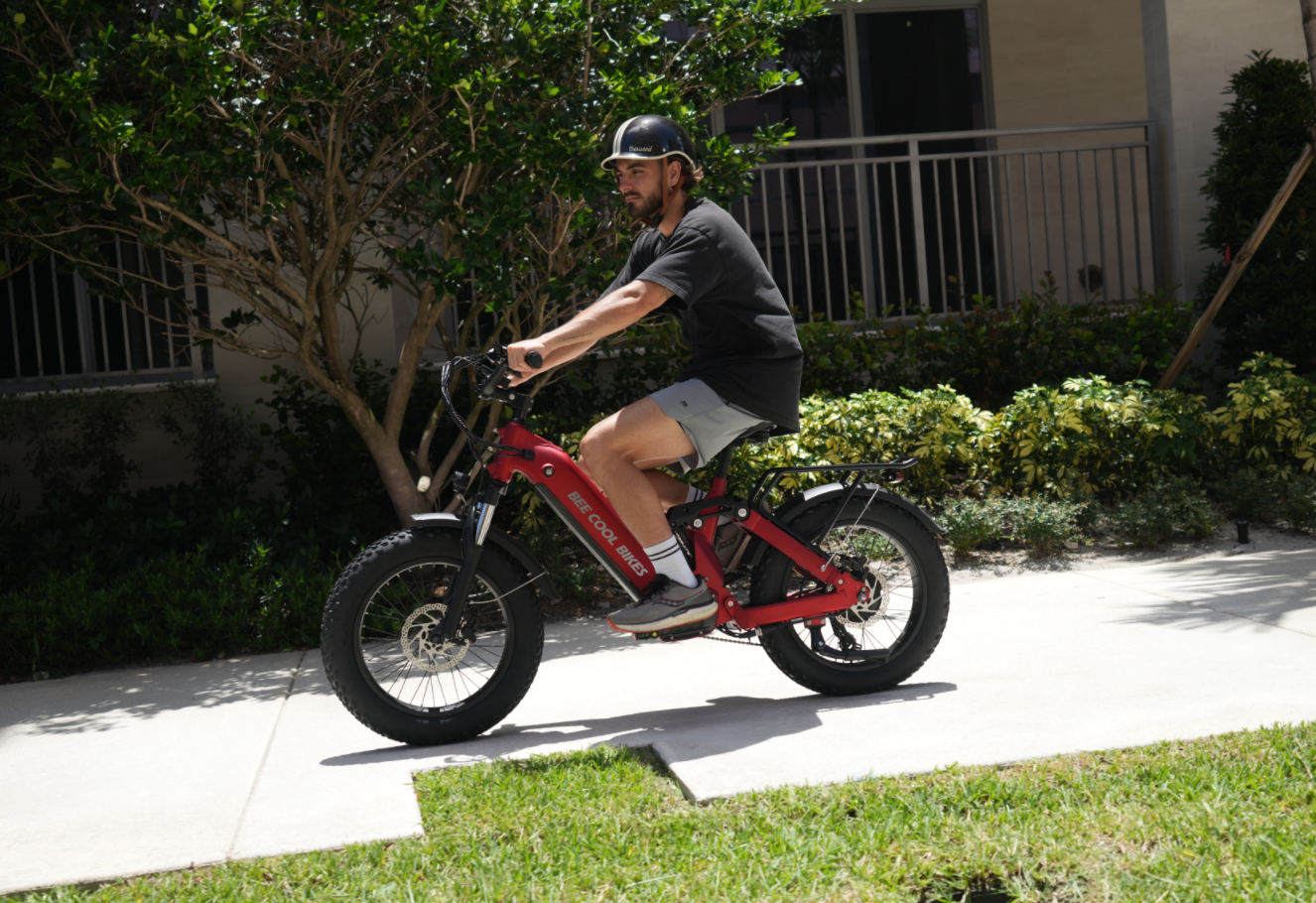 A cyclist riding an electric bike on a sunny trail, wearing a helmet and sunglasses, with a water bottle in the frame – showcasing proper hydration and sun protection during summer rides.